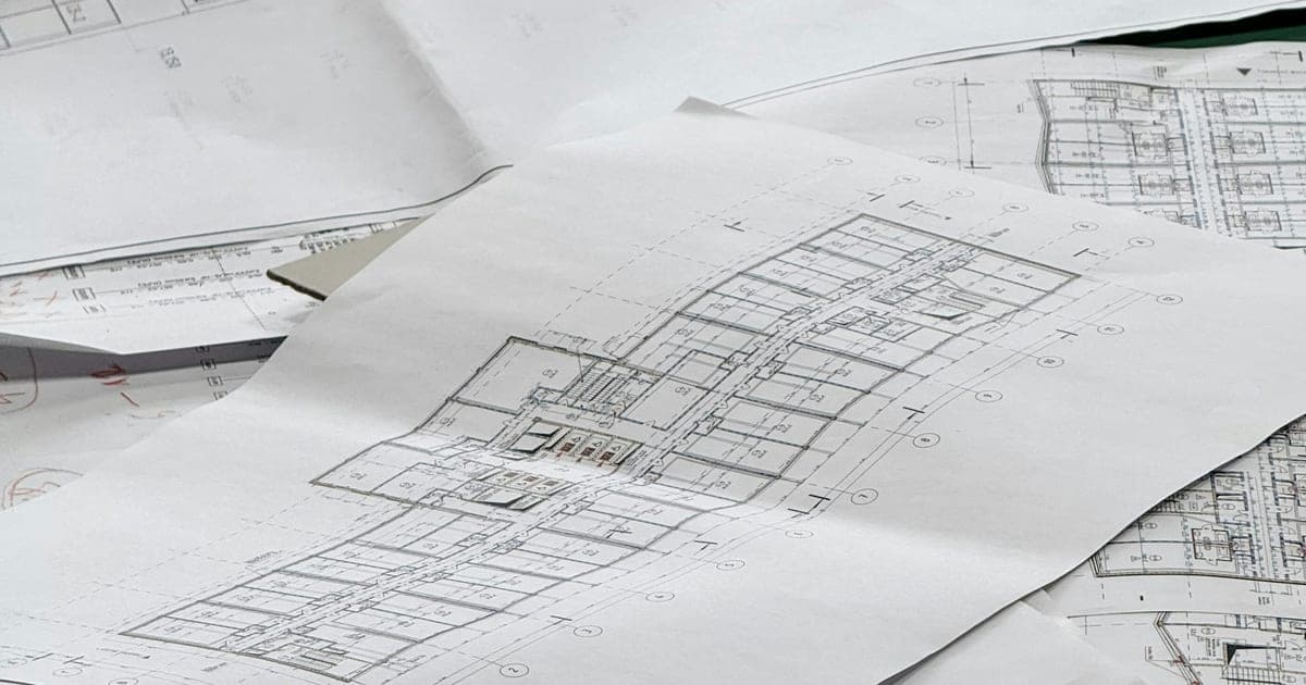 Plans architecturaux et documents techniques étalés sur une table de travail