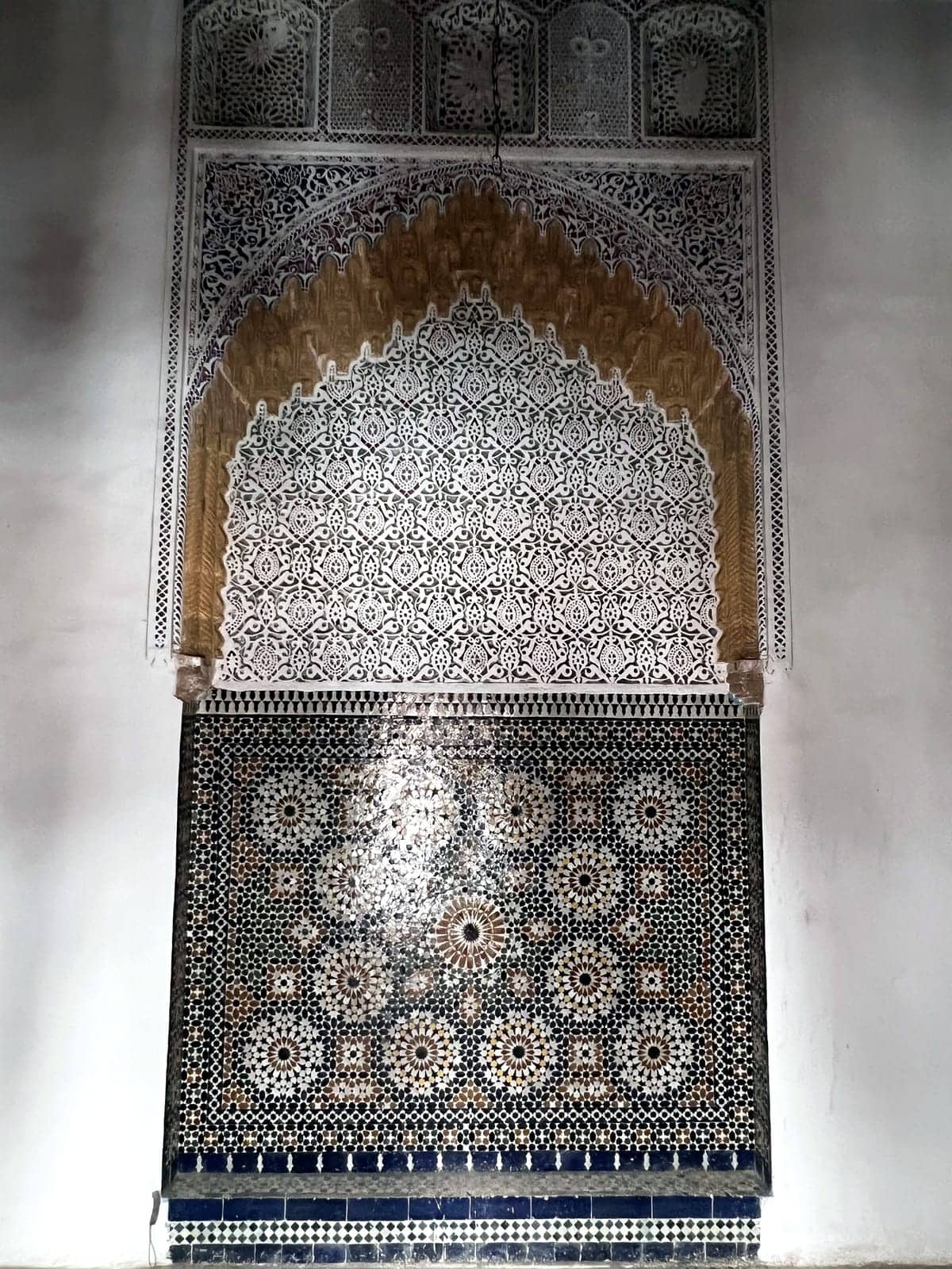 Wall fountain in zellige beneath a carved plaster arch