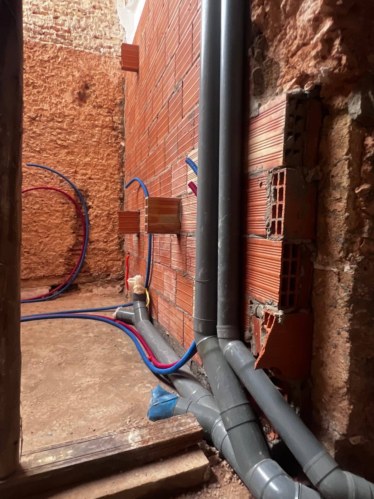 PEX supply pipes and electrical conduits embedded in a brick wall